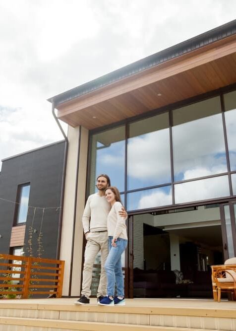 Happy new homeowners standing in front of their recently inspected home in Airlie Beach.