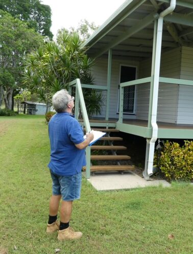Certified building inspector conducting a pre-purchase property assessment in the Whitsundays region.